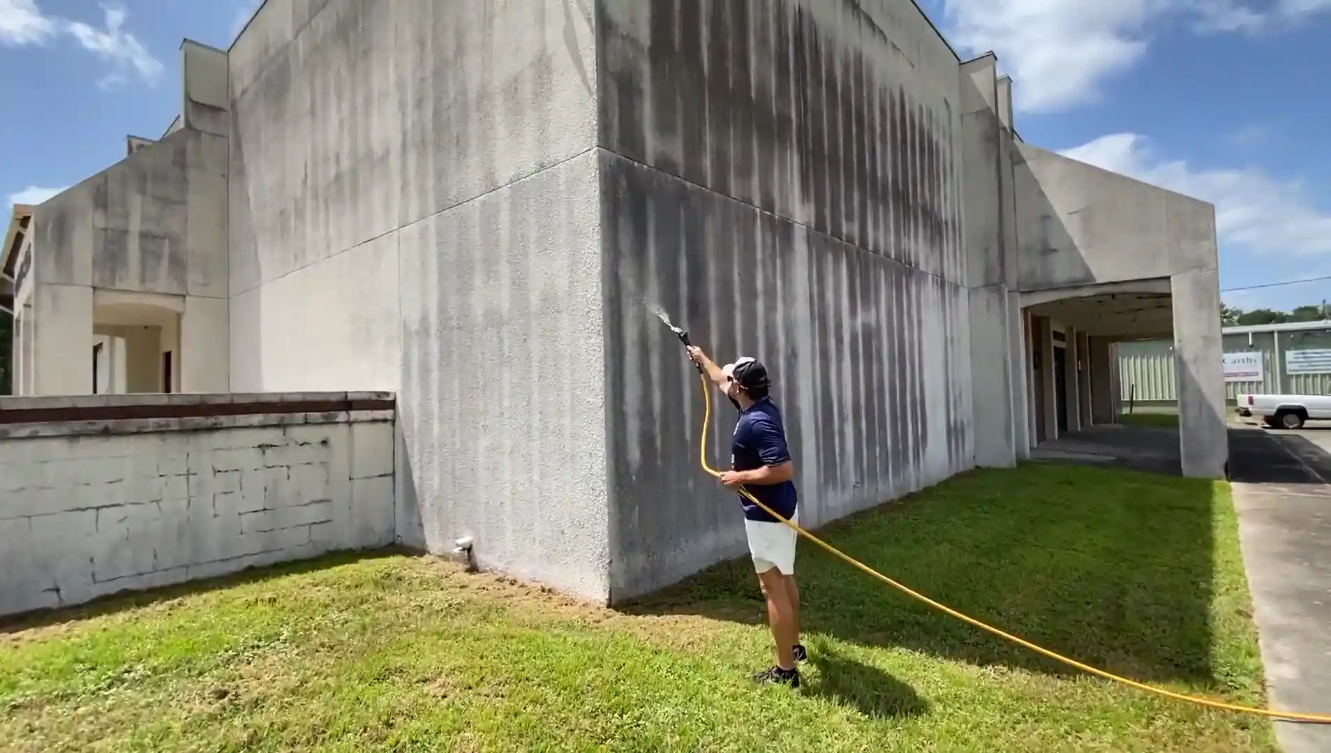Technician soft washing a house exterior wall in Tampa